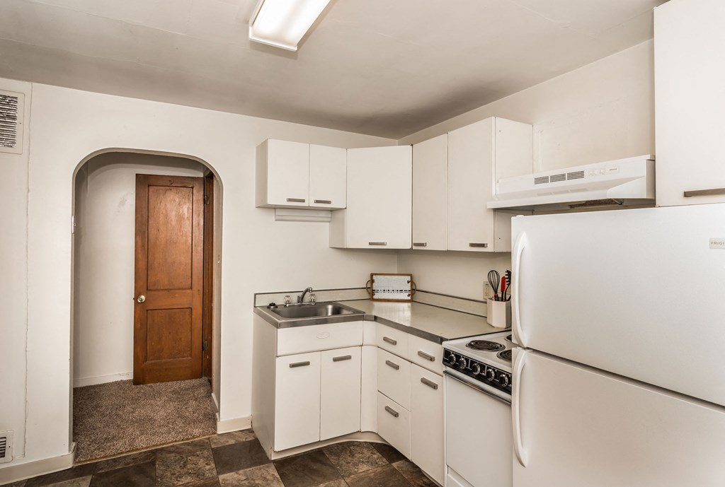 a kitchen with white cabinets and appliances and a refrigerator