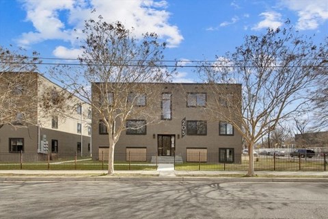 A building with a brown facade and a black fence in front.