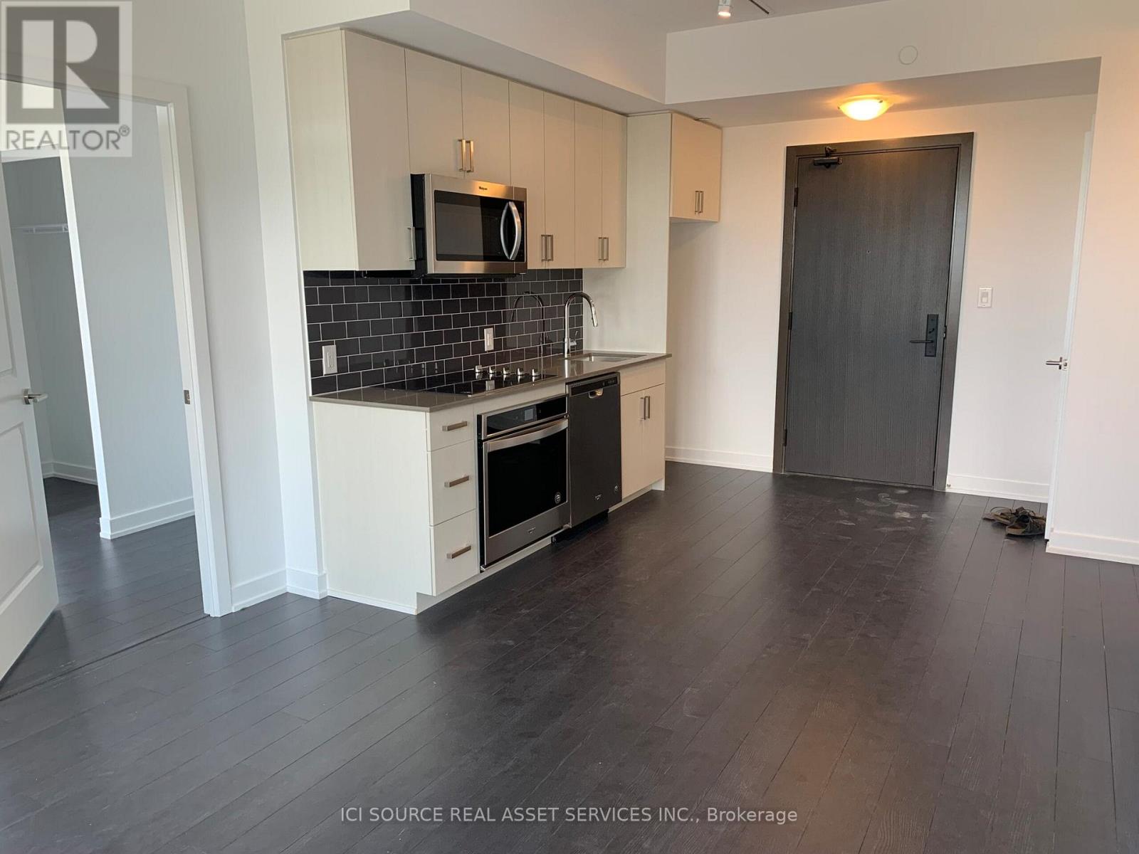 A kitchen with black tile backsplash and white cabinets.