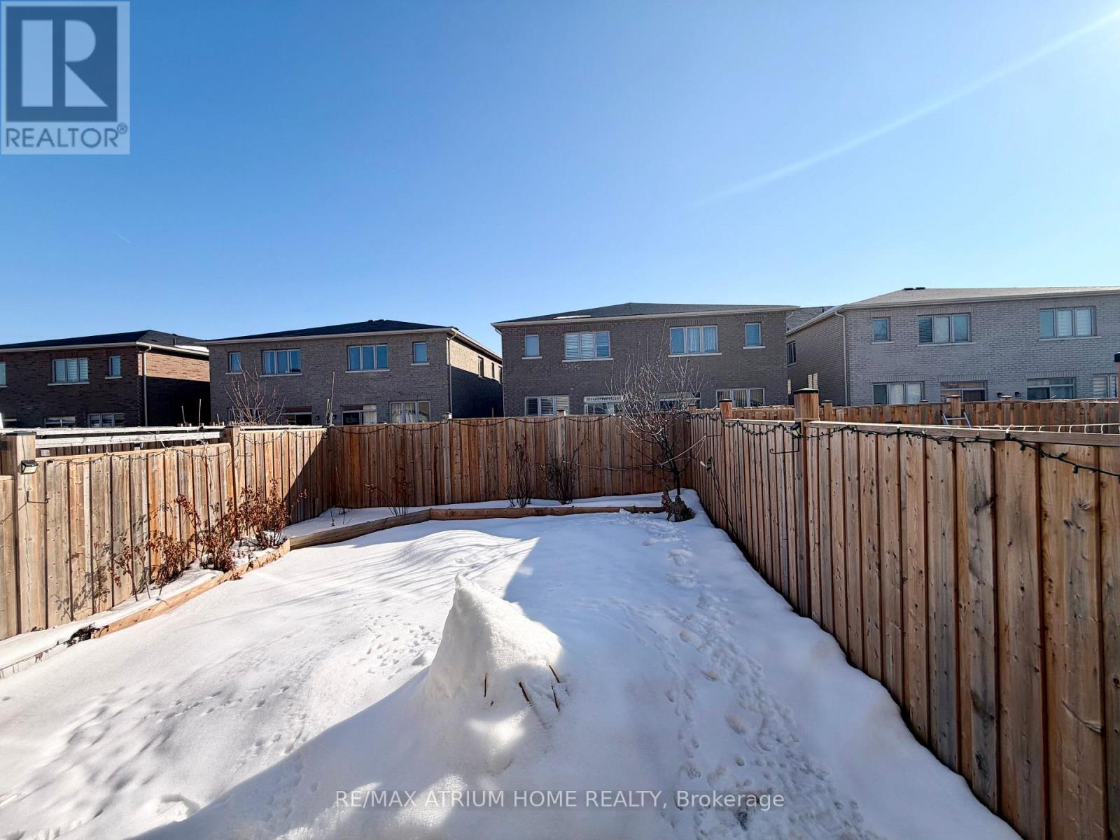 A snow-covered yard in front of apartment buildings.