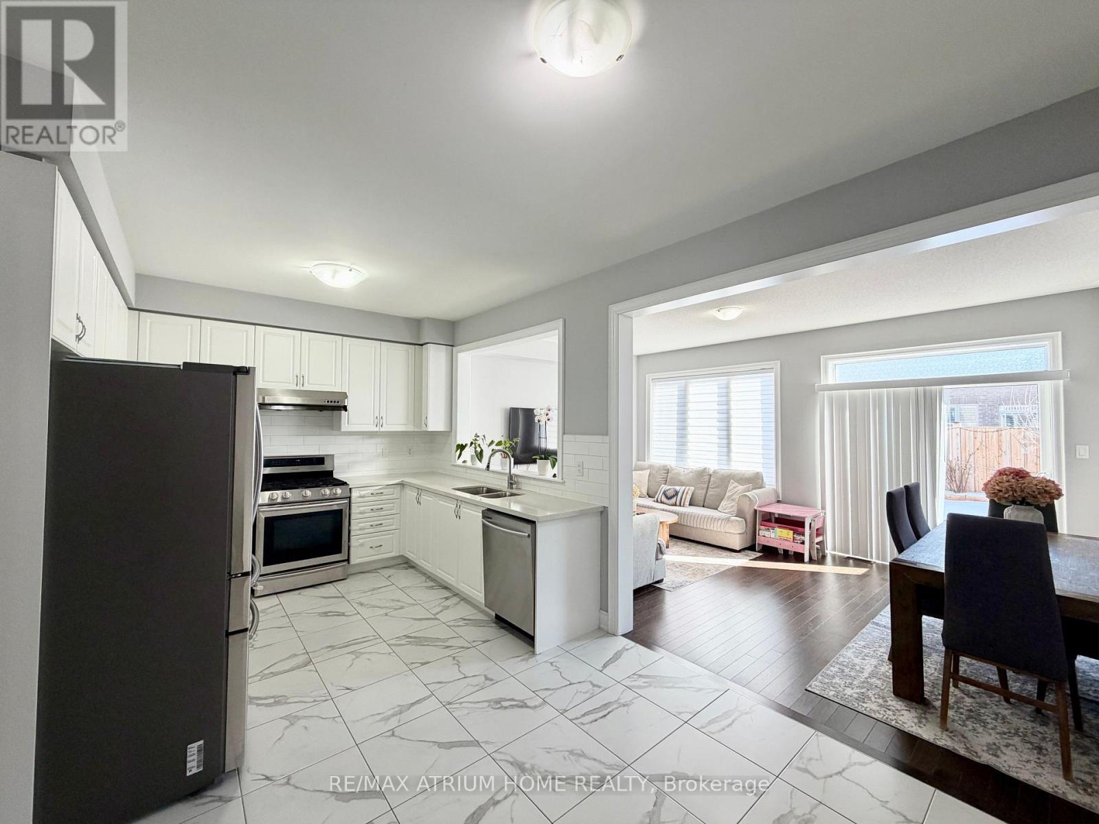 A spacious kitchen with a refrigerator on the left and a dining table with chairs in the foreground.
