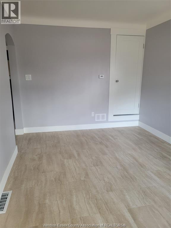 A room with a white door and a light switch on the wall.
