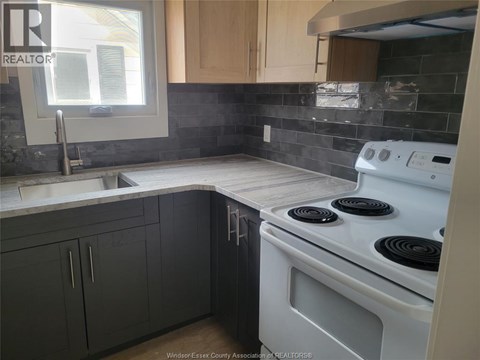 A kitchen with a white stove top oven and a window.