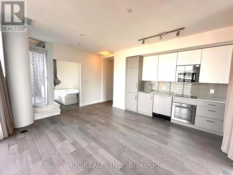 A spacious kitchen with white cabinets and a grey floor.