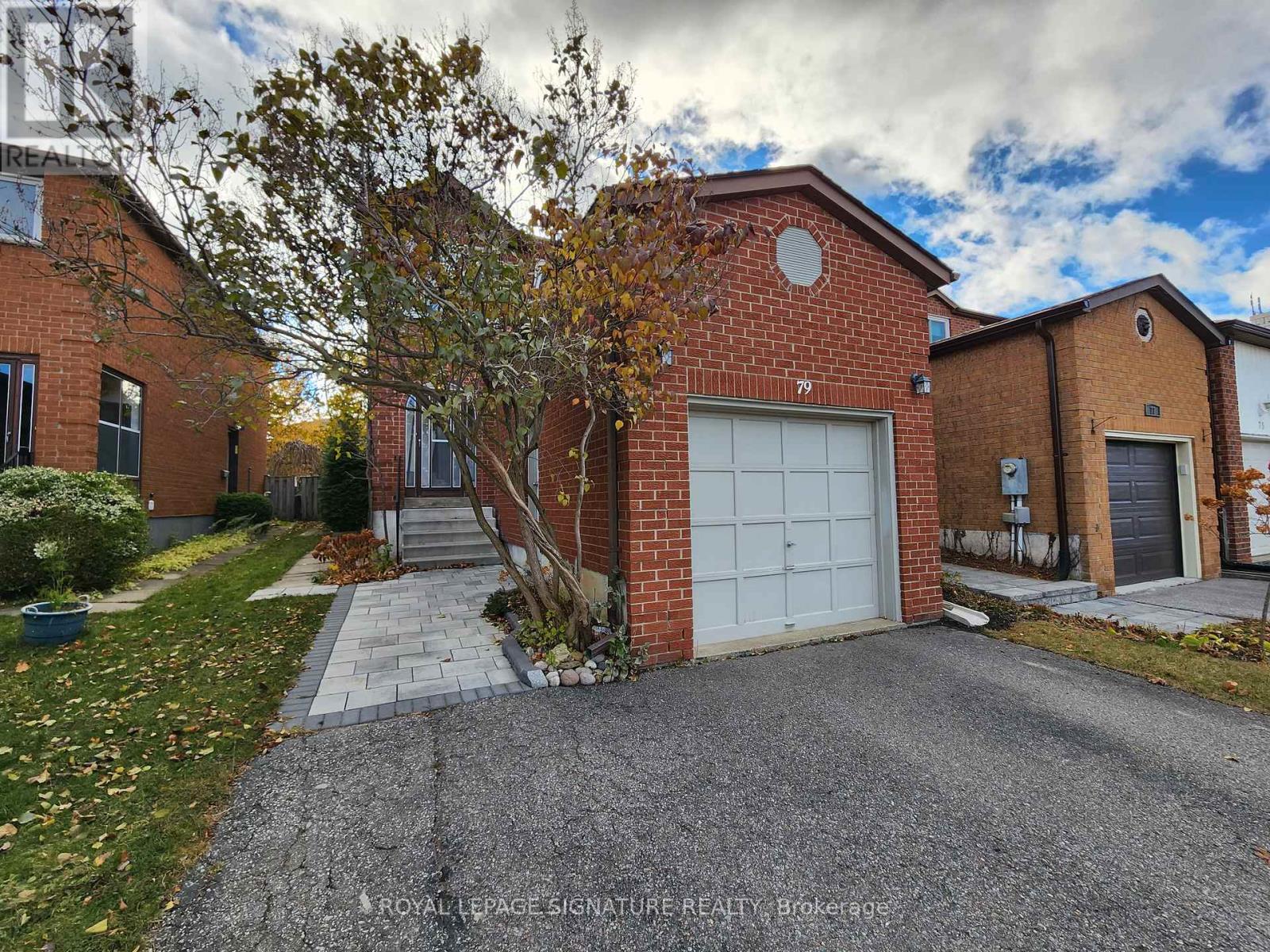 A red brick house with a white garage door is for sale.