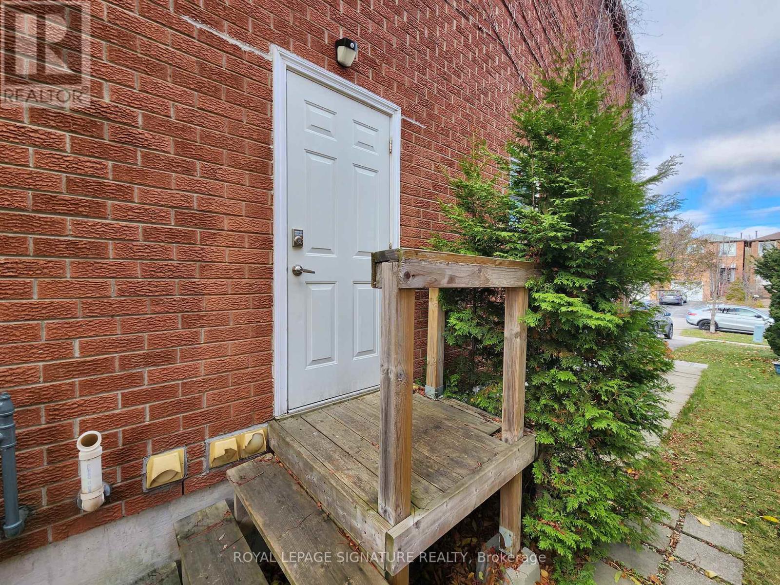 A white door is on the left side of a brick building.