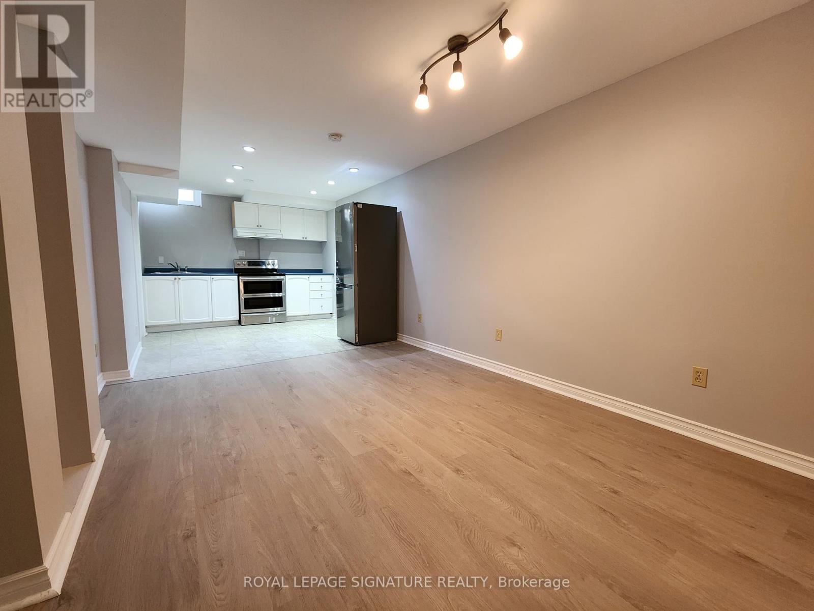 A spacious room with wooden flooring and a ceiling light fixture.