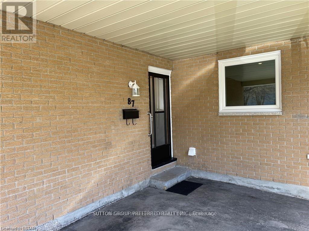 A brick wall with a black door and a small window above it.