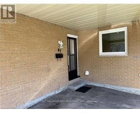 A brick wall with a black door and a small window above it.