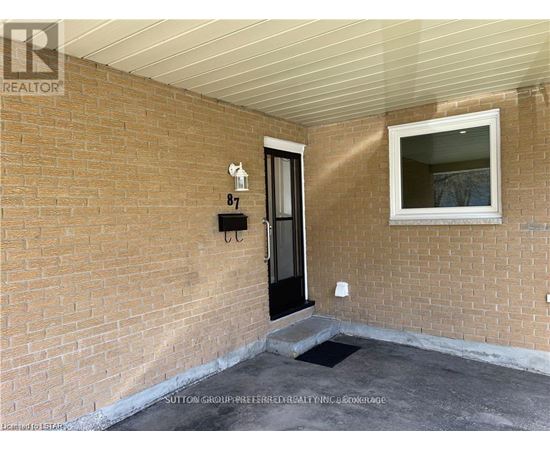 A brick wall with a black door and a small window above it.
