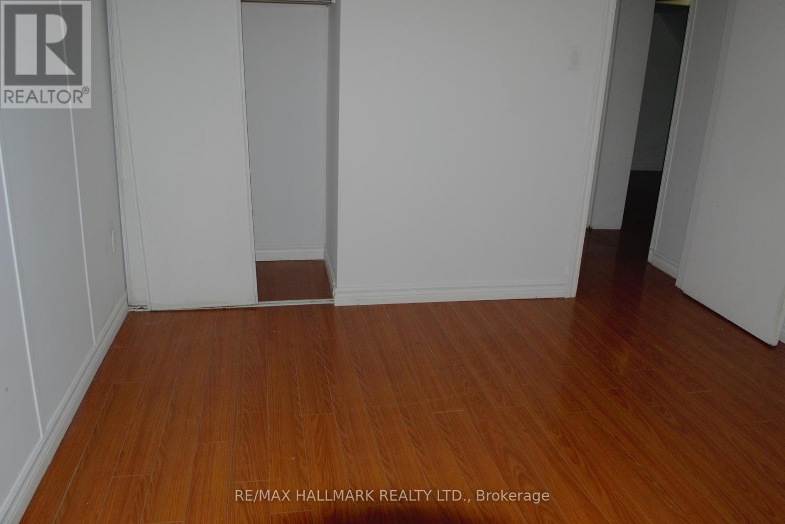 A room with wooden floors and white walls, with a doorway leading to another room.