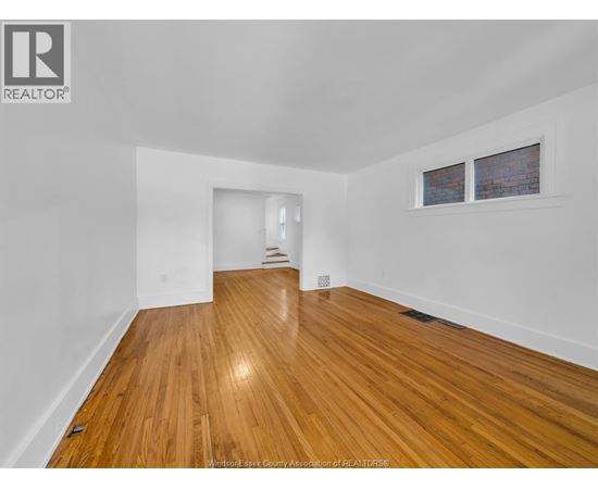 A room with wooden flooring and white walls.