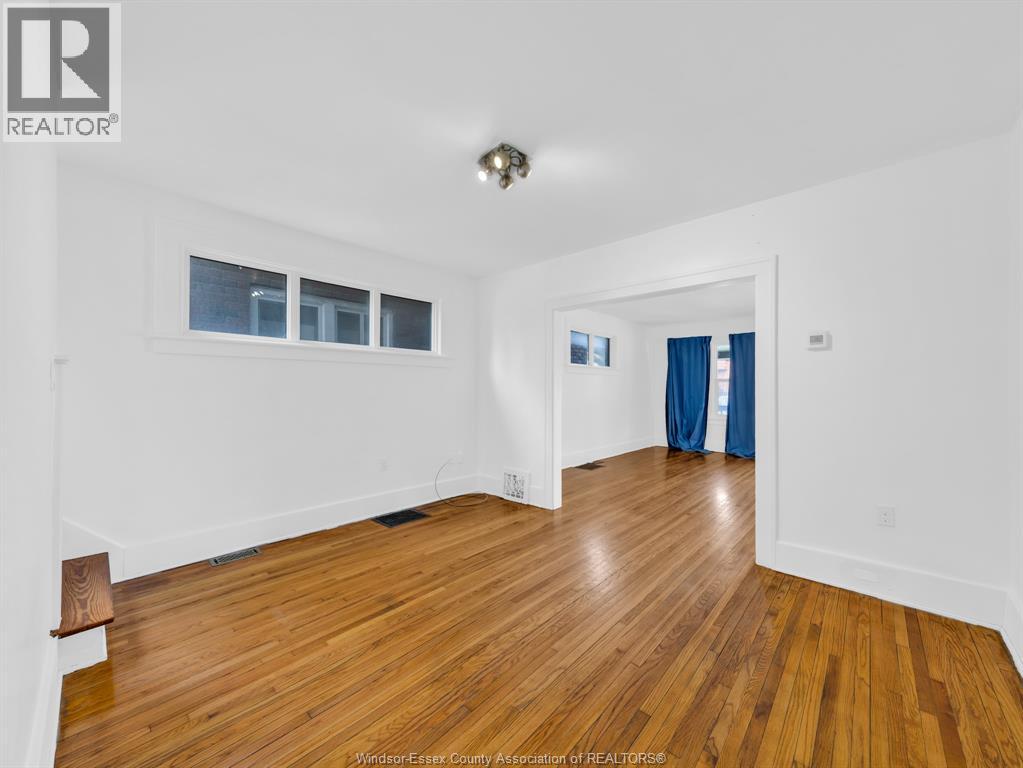 A spacious room with wooden flooring and white walls.