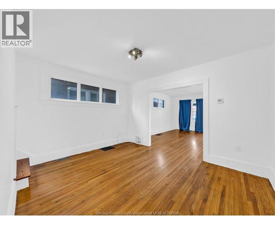 A spacious room with wooden flooring and white walls.