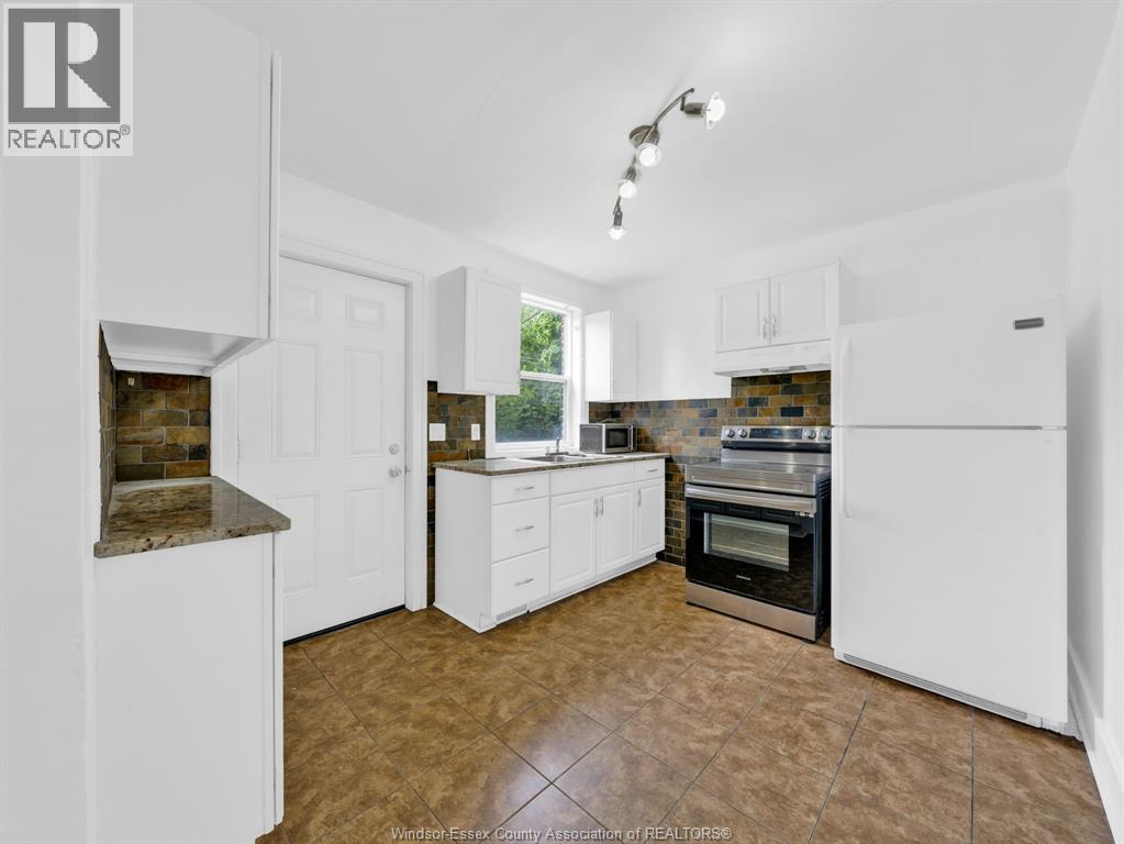 A kitchen with white cabinets and a tiled floor.
