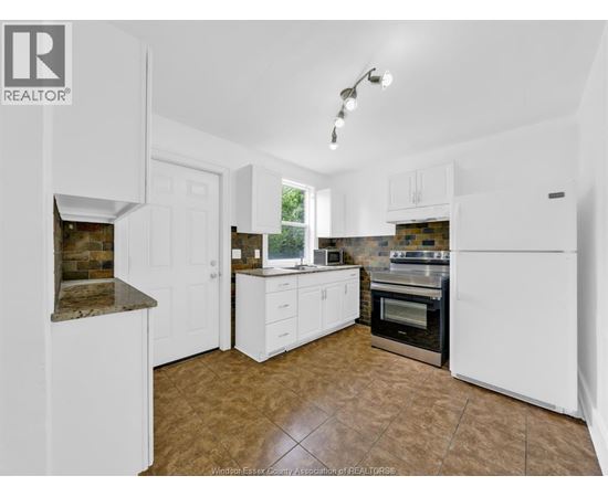 A kitchen with white cabinets and a tiled floor.