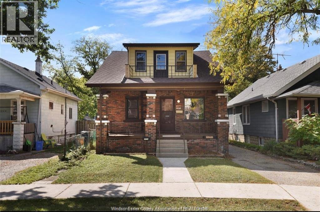 A house with a brown brick facade and a yellow window is for sale.
