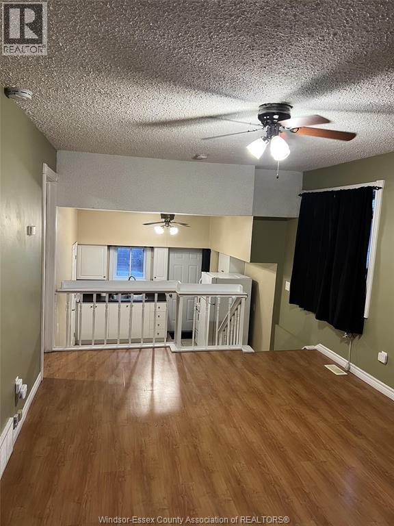 A room with a ceiling fan and wooden flooring.