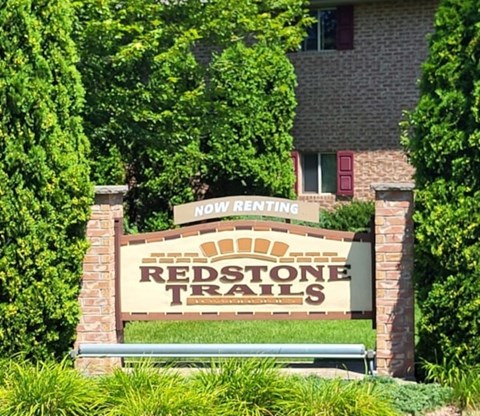 A sign that says Redstone Trails in front of a building.