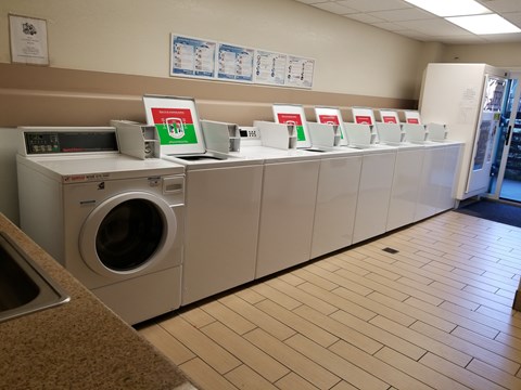 A laundromat with washers and dryers lined up.