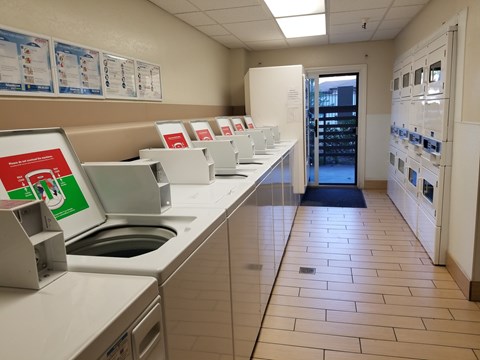 A laundromat with washers and dryers lined up.