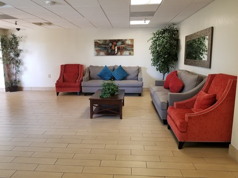 A living room with a red chair and grey couch.