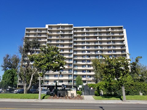 A large apartment building with a parking lot in front.