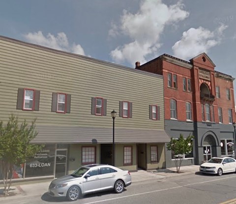 A street view of a building with a car parked in front.