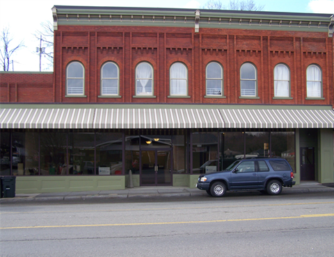 A blue car is parked in front of a red building.