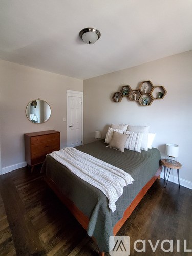 A bedroom with a bed, a mirror, and a wooden floor.