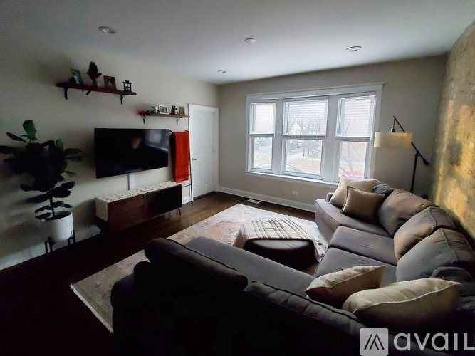 A living room with a grey couch and a television on the wall.