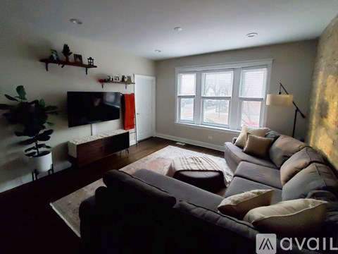A living room with a grey couch and a television on the wall.