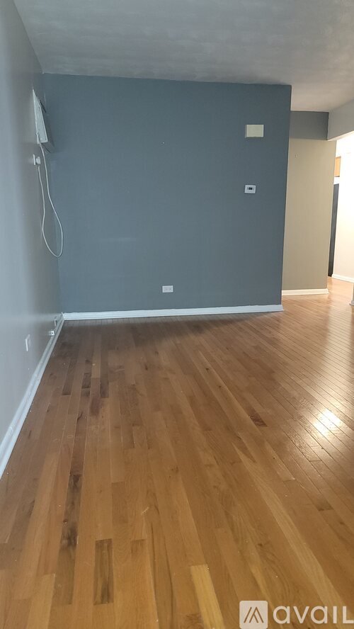 A room with wooden flooring and a wall socket.