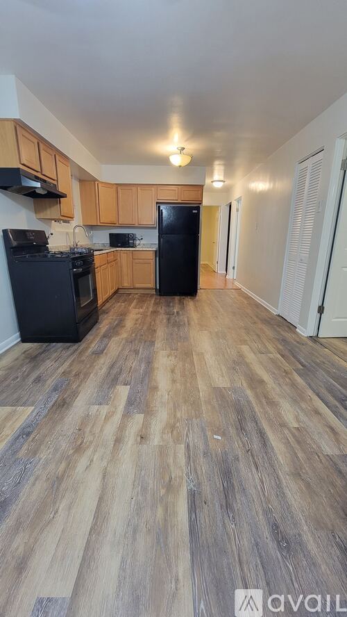 A kitchen with wooden floors and black appliances.