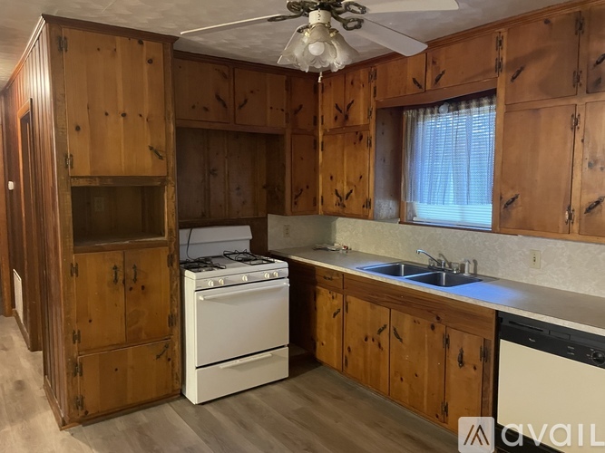 A kitchen with wooden cabinets and a white stove top oven.