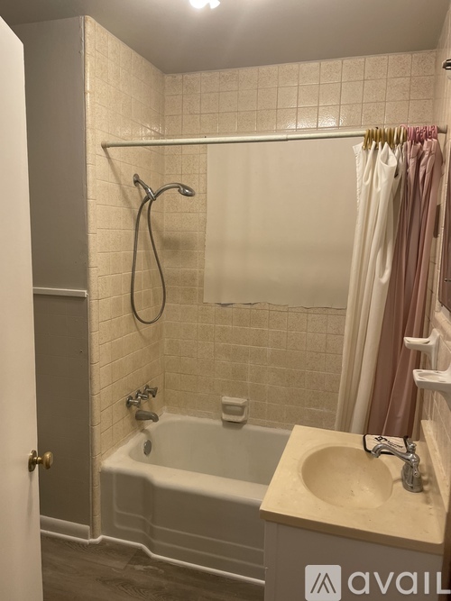 A bathroom with a white tub, sink, and tiled walls.