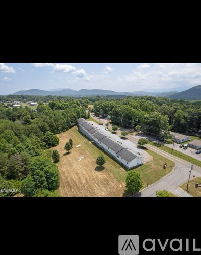 A large building surrounded by trees with a mountain in the background.