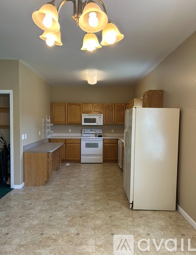 A kitchen with a white refrigerator and wooden cabinets.