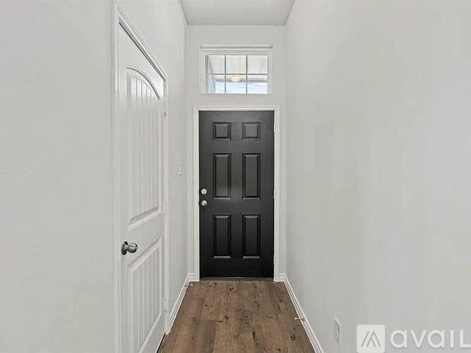 A black door is in the middle of a white wall.