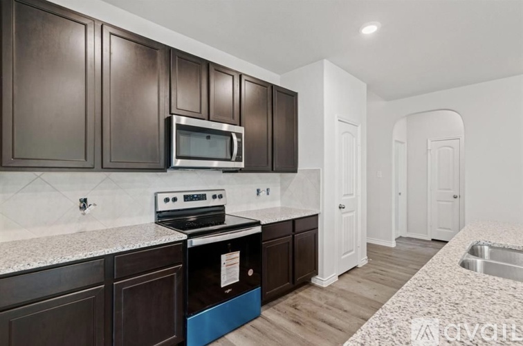 A kitchen with dark brown cabinets and a stove top oven.