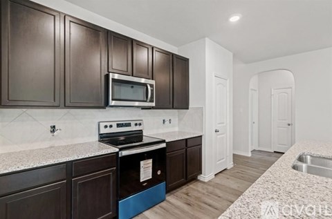 A kitchen with dark brown cabinets and a stove top oven.