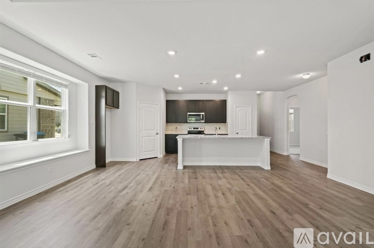 A spacious room with wooden flooring and white walls.