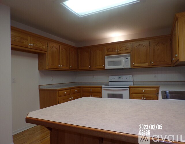 A kitchen with wooden cabinets and a white microwave above the stove.