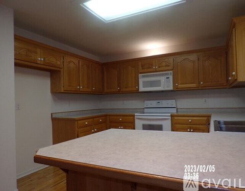 A kitchen with wooden cabinets and a white microwave above the stove.