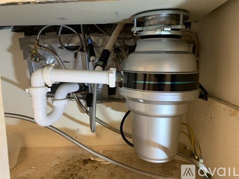 A silver and white kitchen sink with a silver drain cover and a white pipe.
