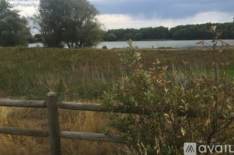 A wooden fence in the foreground with a lake and trees in the background.