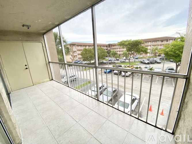 A balcony with a view of a parking lot and buildings.