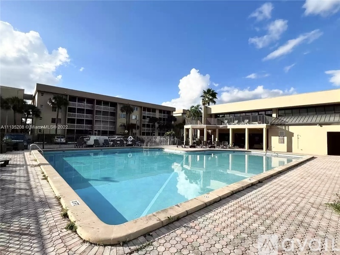 A large swimming pool surrounded by a brick patio.