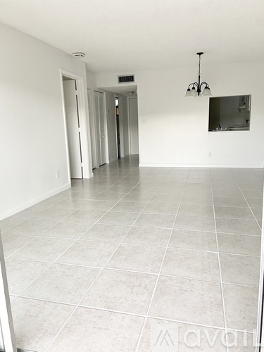 A spacious room with white walls and tile flooring.