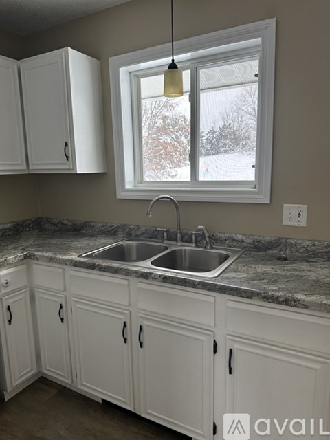 A kitchen with a marble countertop and white cabinets.